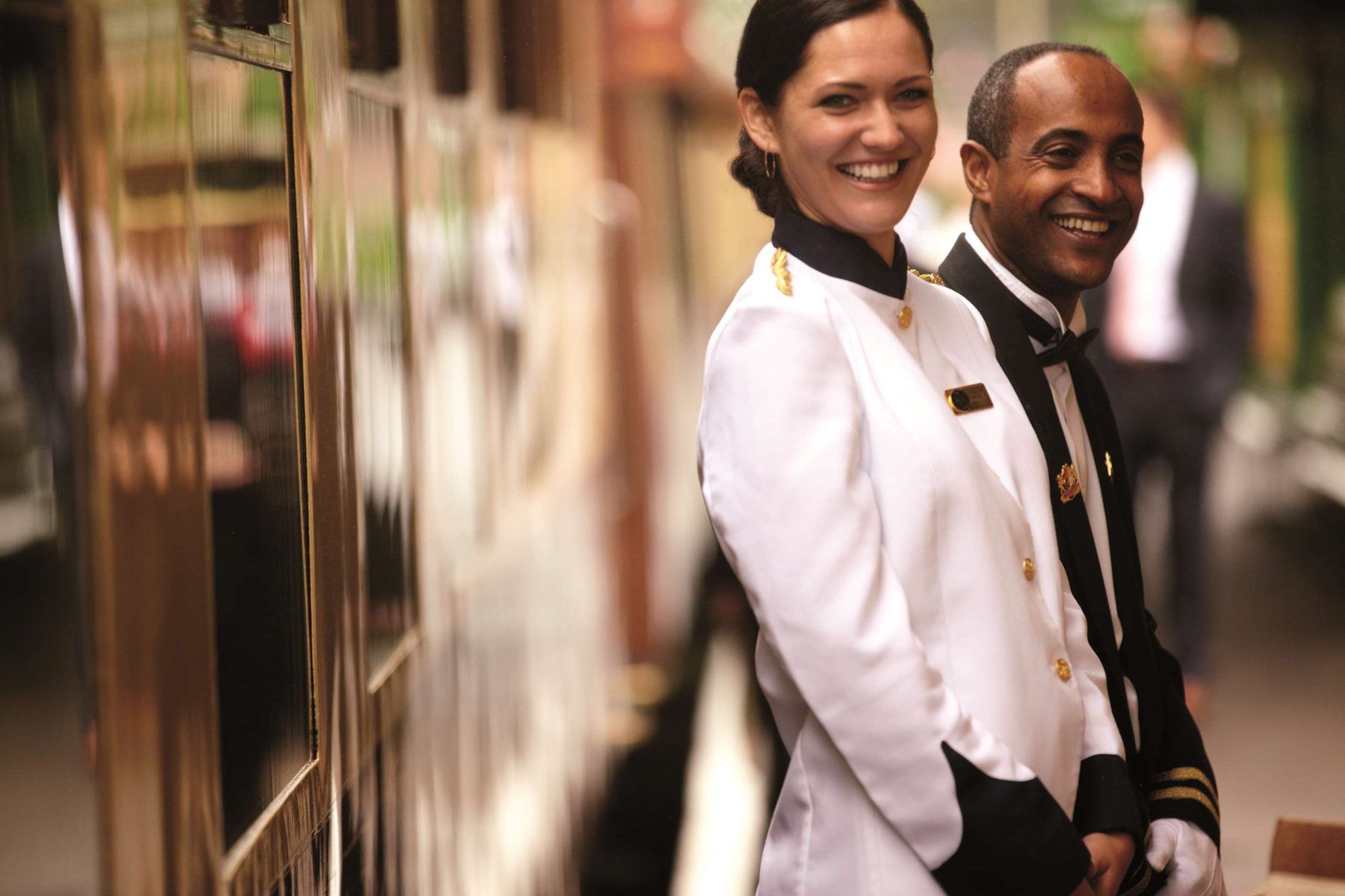 Two hospitality hosts in white jackets, smiling